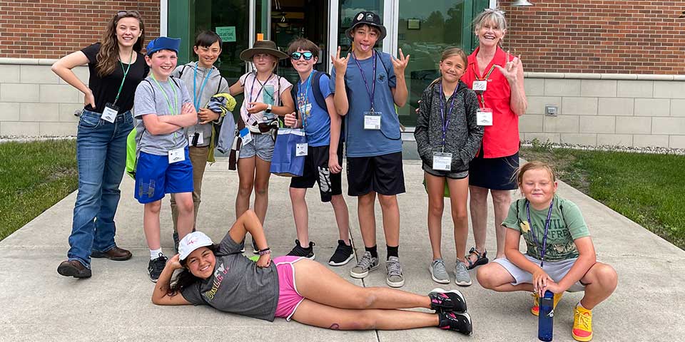 Campers and staff posing in front of a building